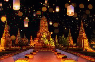 Glowing paper lanterns floating over the ancient Buddhist temples of Ayutthaya, Thailand at night.