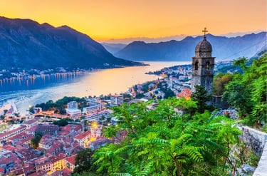 Sunset view over the Bay of Kotor in Montenegro with historic church tower and mountain scenery.