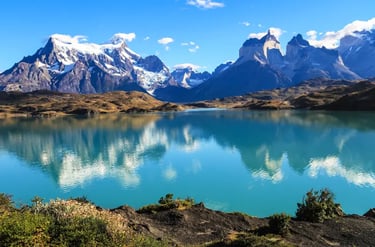 Snow-capped peaks of Torres del Paine reflected in a turquoise lake in Chilean Patagonia.