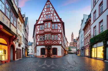 Historic half-timbered building in Mainz old town with cobblestone streets and the cathedral in the distance.
