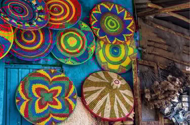 Handwoven Ethiopian colorful wicker baskets and traditional flat plates hanging on a blue wall.