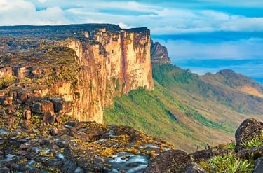 Panoramic view of Mount Roraima's vertical cliffs and flat sandstone summit under a blue sky.