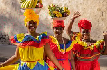 Colombian Palenqueras in traditional colorful dresses balancing fruit baskets on their heads in Cartagena.