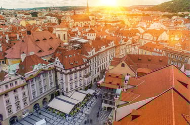 Sunset over Prague Old Town Square featuring historic red rooftops and European architecture.