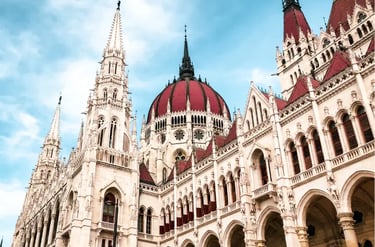 Ornate Gothic Revival architecture and red domes of the Hungarian Parliament Building in Budapest.