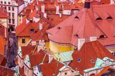Aerial view of historic Prague architecture featuring traditional orange terracotta tile rooftops and cobblestone streets.