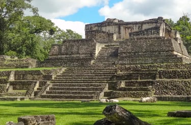 Ancient Mayan ruins of Caracol in Belize featuring a stone pyramid temple with stairs.
