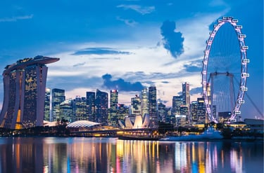 The illuminated Singapore city skyline at twilight featuring the Marina Bay Sands and Singapore Flyer.