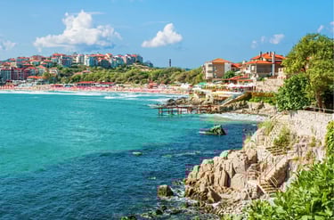 Panoramic view of the Black Sea coastline in Sozopol, Bulgaria, featuring a rocky shore and sandy beach.