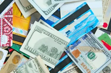 A scattered pile of US hundred dollar bills and multiple credit cards representing personal finance and debt.