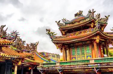 Ornate Chinese temple roof with colorful dragon carvings and traditional architecture under a cloudy sky.