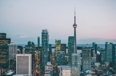 Panoramic evening view of the Toronto skyline featuring the illuminated CN Tower and downtown skyscrapers.