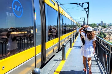 Lili walking along the Dom Luís I Bridge as a train passes by on a sunny day in Porto.