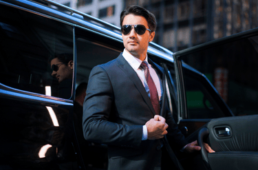 Man in a suit stepping out of a black car for a negotiation.