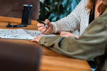 une femme est assise à une table montrant un dessin à son associée