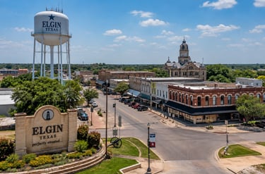 Elgin TX downtown skyline featuring the Elgin water tower, historic buildings, local streets