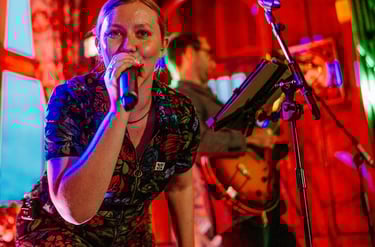 a woman in a floral dress singing into a microphone