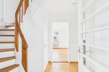 Heller, moderner Flur mit Eichenparkett und einer Holztreppe, die nach oben führt.