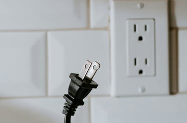 An electric cord being pulled out of the wall to prevent phantom energy.