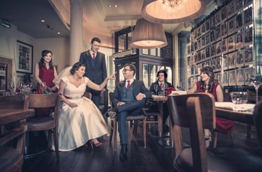 A bride and groom celebrating their wedding reception with guests in a stylish restaurant setting.