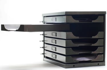 A black and white image of a set of documents drawers with one open drawer