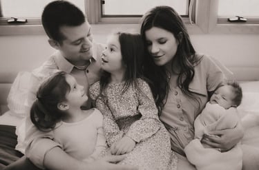 Black and white photo of the full family on the master bed during a Grand Rapids newborn session.