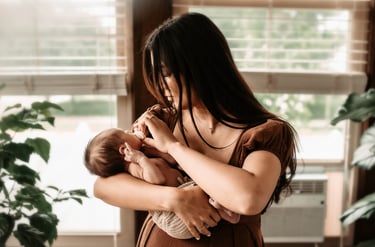 Mother cradling newborn son by a window at home in Hibbing, MN