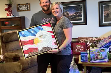 a man and woman holding a picture of a painting of a bald eagle