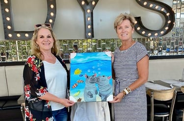 a woman holding a painting of a hippo