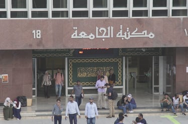 a group of people walking down a street Infront of a library 