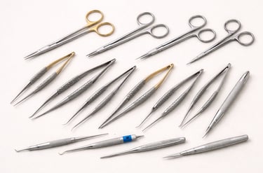 Microsurgical instruments like small scissors, forceps, and needle holders on a white background.