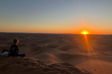Traveller seated on Erg Chigaga dune at sunset, Morocco’s largest sand sea