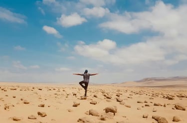 A woman stands on one leg doing a yoga move in the desert