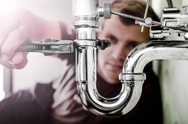 Un plombier ressert un siphon de lavabo