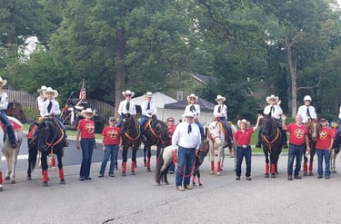 A group of people on and off horses waiting for a parade to start.