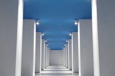 Long modern hallway with white columns and blue ceiling.