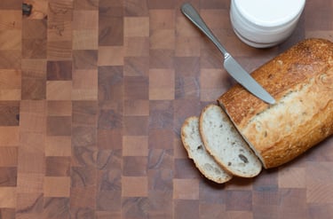 End-grain chopping board styled with sliced bread, a knife and a butter dish