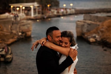 durante la sessione fotografica di coppia, gli sposi si abbracciano teneramente sullo sfondo di un canale al tramonto