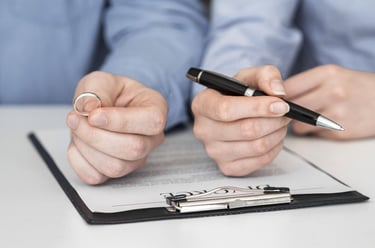 a man and woman holding a pen and writing on a piece of paper