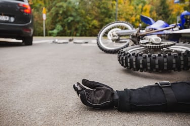 Motorcycle Accidents scene showing a rider’s gloved hand on the road and a fallen motorcycle after a collision, illustrating