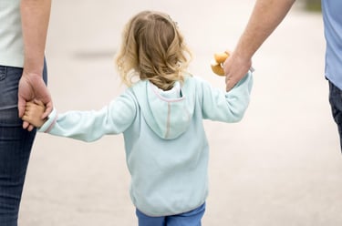 Adoption and guardianship concept, young child holding hands with two adults, representing family ca