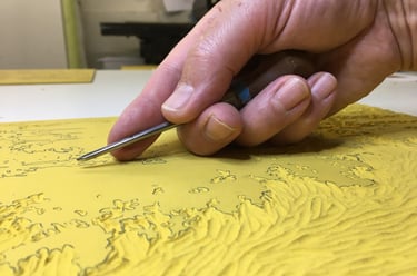 Phtographie de main gravant une plaque de linoléum