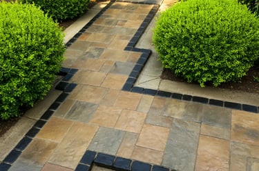 Trottoirde dalles et pavé avec bordure noire et buissons bien taillés par M2 Paysage