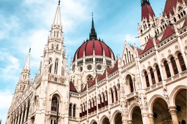 Ornate Gothic Revival architecture and red domes of the Hungarian Parliament Building in Budapest.