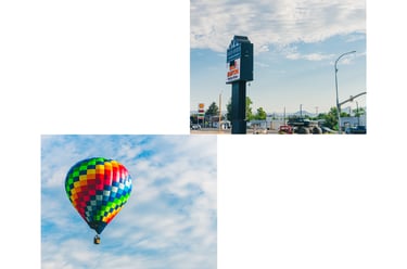 A colorful rainbow checkered hot air balloon floats in a blue sky above a Shell gas station sign.