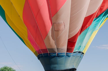 A group of people preparing a colorful hot air balloon for flight in a grassy field.