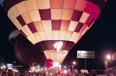 A glowing hot air balloon illuminates the crowd at the Dinah Soar Days Balloon Festival at night.