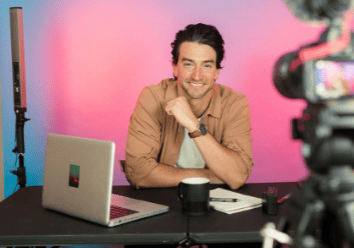 a man sitting at a table with a laptop and a camera