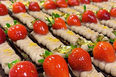 Gourmet chocolate cake slices topped with mocha cream, fresh glazed strawberries, and edible gold leaf.