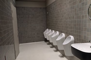 Modern unisex restroom interior—minimalist design, open space, six urinals visible